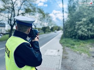 na zdjęciu umundurowany policjant ruchu drogowego, który dokonuje pomiaru prędkości