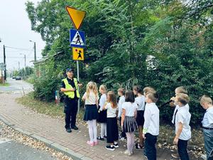 na zdjęciu policjant rozmawia z dziećmi przy przejściu dla pieszych