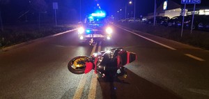 na zdjęciu leżący na jezdni motocykl a za nim radiowóz policji