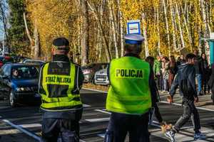 na zdjęciu umundurowany policjant ruchu drogowego wraz ze strażnikiem miejskim obserwują przejście dla pieszych