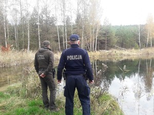 na zdjęciu umundurowany policjant wsólnie ze strażnikiem straży leśnej