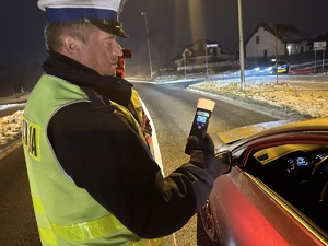 na zdjęciu umundurowany policjant pokazuje urządzenie do badania trzeźwości