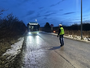 na zdjęciu umundurowany policjant zatrzymuje do kontroli autobus