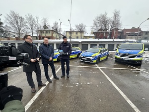 na zdjęciu mężczyzna dwóch mężczyzn i jeden umundurowany policjant, który trzyma w ręce kartę od pojazdu służbowego