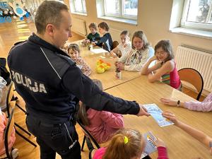 na zdjęciu policjant który przekazuję ulotkę