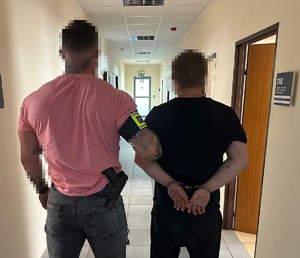 na zdjęciu nieumundurowany policjant trzyma zatrzymanego mężczyznę