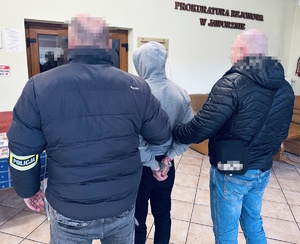 na zdjęciu dwóch nieumundurowanych policjantów trzymających zatrzymanego mężczyznę w budynku prokuratury