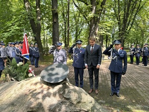 na zdjęciu umundurowani policjanci oddają honor pod obeliskiem wspólnie z przedstawicielem władz miasta