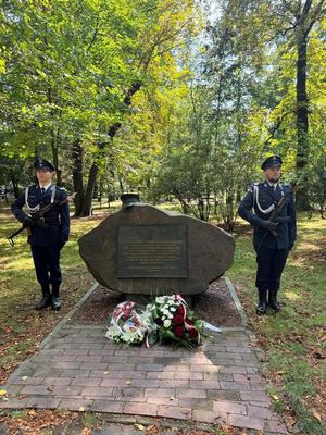 Kolorowe zdjęcie przedstawiające dwóch funkcjonariuszy Policji pełniących wartę przy obelisku  „Pamięci Funkcjonariuszy 7. Kompanii Rezerwy Policji Państwowej.&quot;