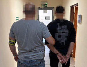 na zdjęciu nieumundurowany policjant trzyma zatrzymanego mężczyznę