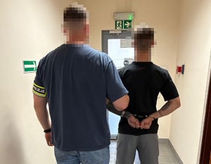 na zdjęciu nieumundurowany policjant trzyma zatrzymanego mężczyznę