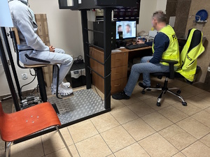 na zdjęciu technik kryminalistyki wykonuje czynności z zatrzymanym mężczyzną