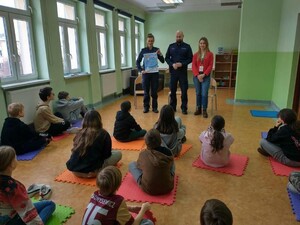 umundurowaniu funkcjonariusze i przedstawicielka sanepidu prowadzą prelekcje z dziećmi - uczestnikami półkolonii
