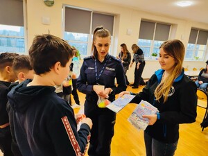 funkcjonariusz Policji z przedstawicielką Sanepidu rozdają książeczki "Bezpieczne Ferie"