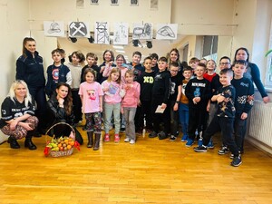 Zdjęcie grupowe funkcjonariusza Policji, przedstawicielki Sanepidu oraz dzieci z półkolonii.