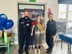 na zdjęciu policjanci z uczennicą która trzyma tarczę policyjną i ma założony kask