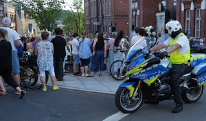 na zdjęciu policjant umundurowany na motocyklu stoi za tłumem ludzi