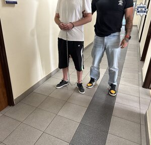 na zdjęciu nieumundurowany policjant trzyma zatrzymanego mężczyznę w kajdankach zespolonych